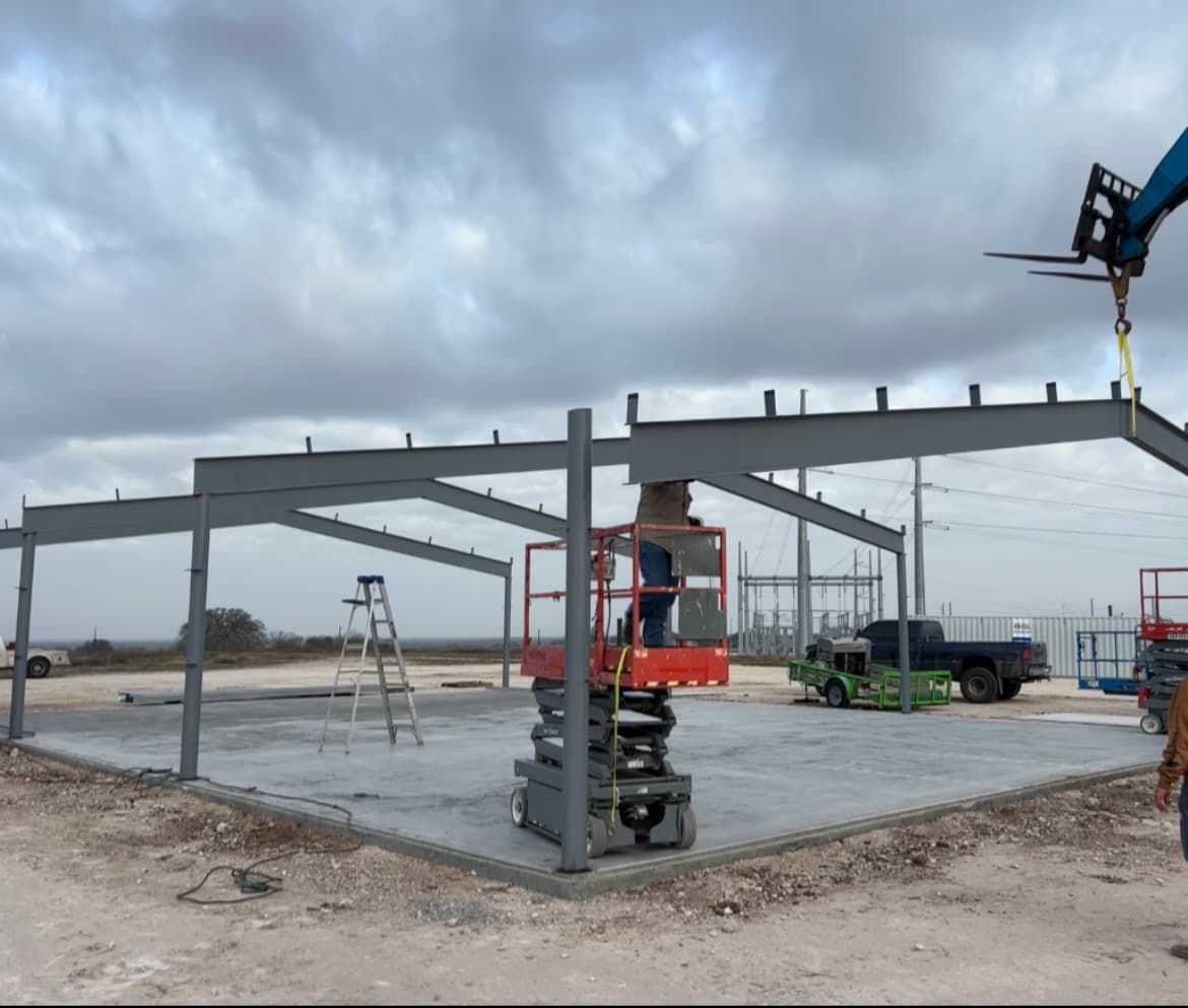 Telehandler setting a steel rafter during early-stage frame erection on an SSG project